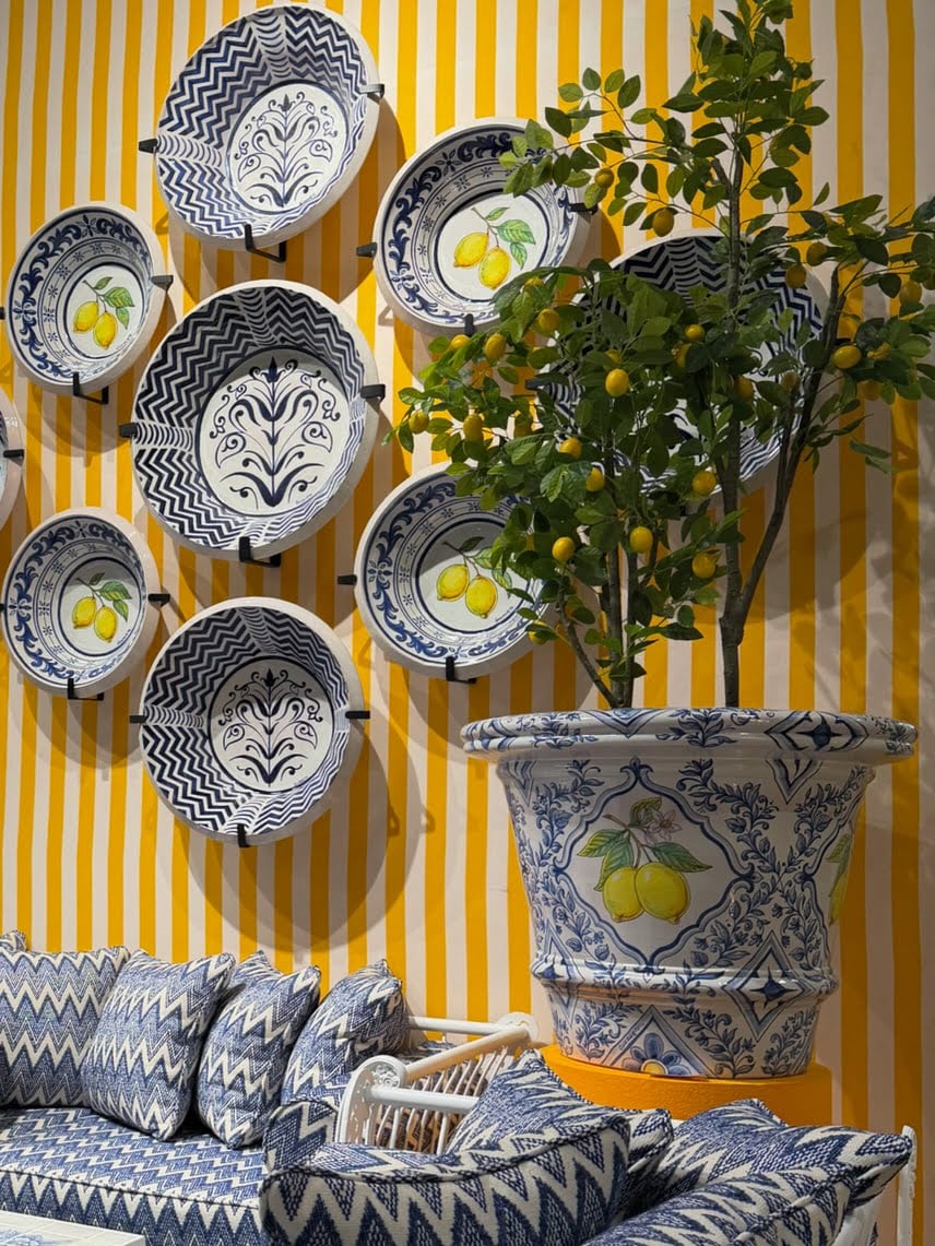 Blue and white decorative plates and a lemon tree displayed against a yellow and white striped wall 