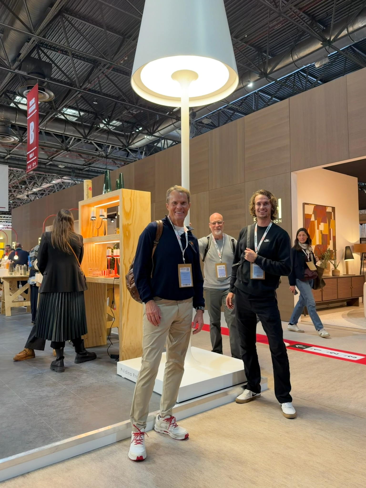 Three people standing under a large lamp display at a trade show booth