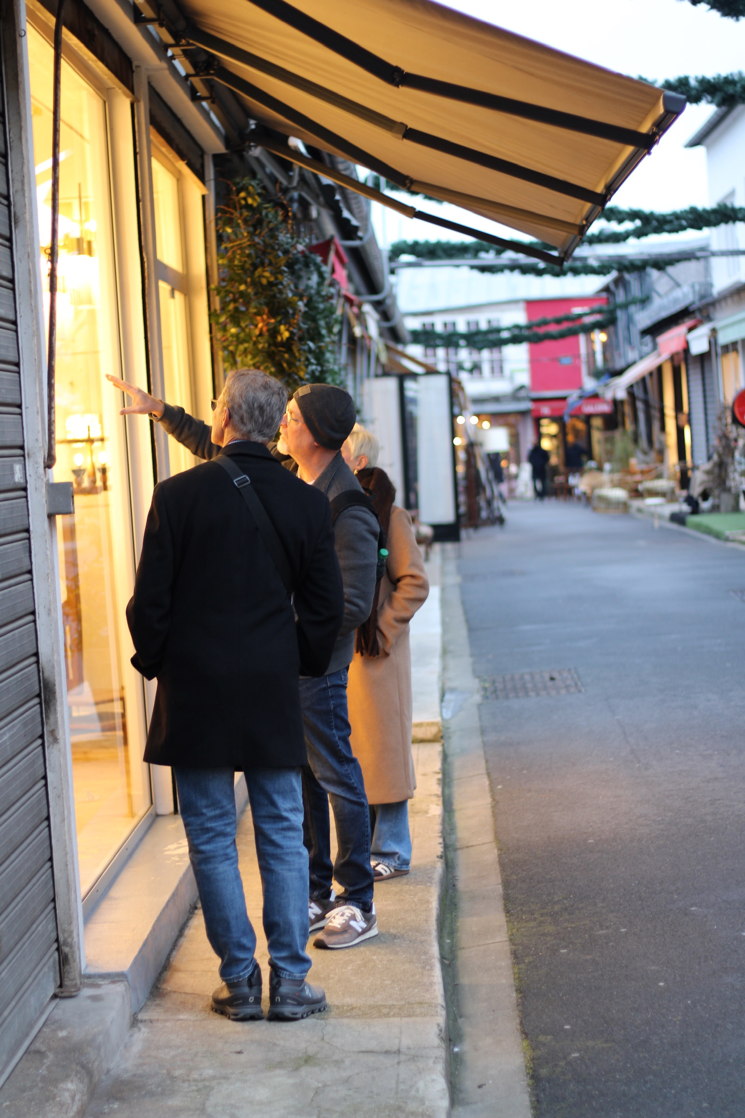  Two people standing on a quiet street, looing at and pointing toward a warmly lit shop window display