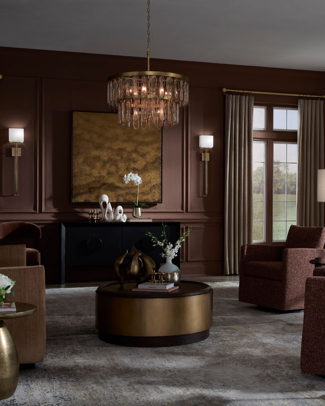 Moody living room with dark wood-paneled walls, a brass and glass chandelier, and a round coffee table surrounded by upholstered chairs.