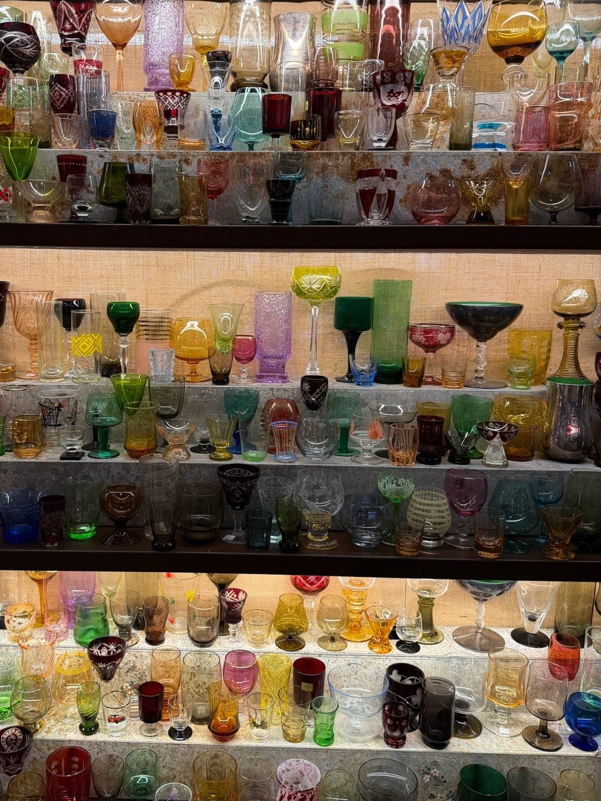 Shelves filled with colorful vintage glassware in a variety of shapes and patterns